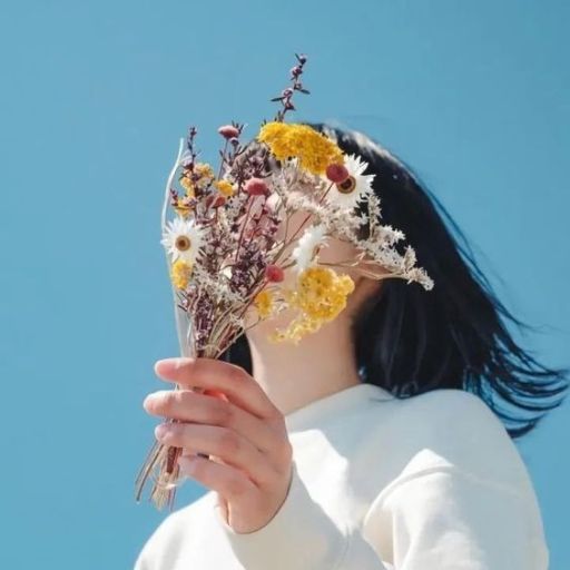 a woman holding a bunch of flowers up to her face