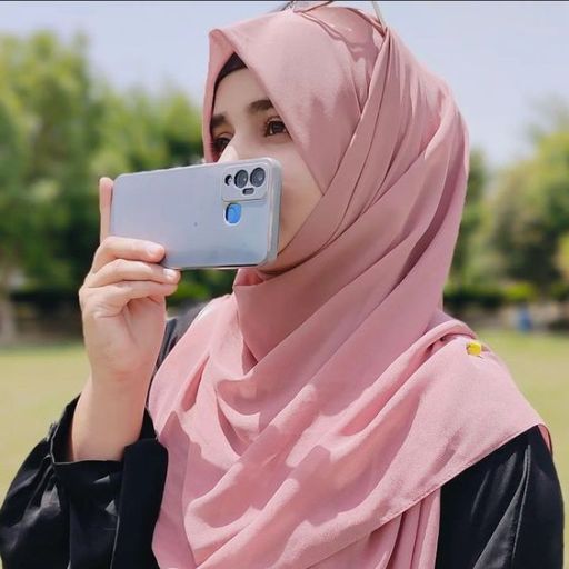 a woman in a hijab taking a picture with her cell phone
