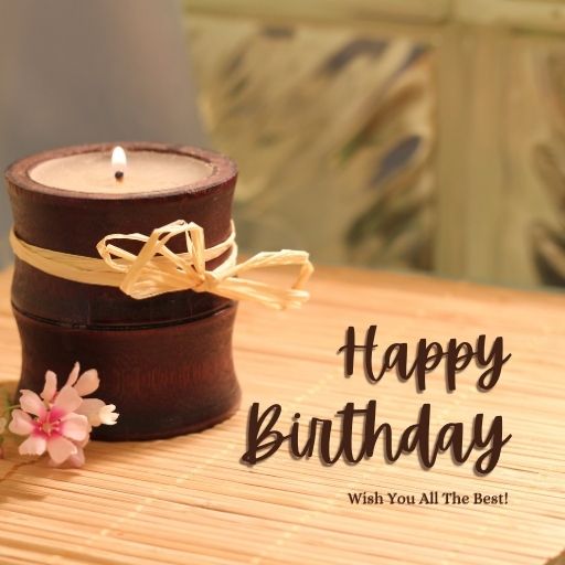 Happy birthday greeting card with a lit candle in a bamboo holder, a pink flower, and a wish for all the best.