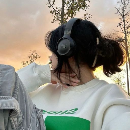 a woman wearing headphones standing next to a tree