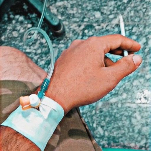 a man wearing a medical bracelet holding a cigarette