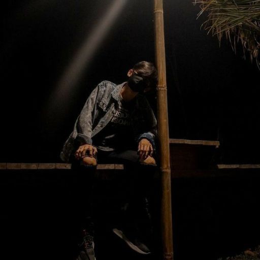 a person sitting on a ledge under a street light