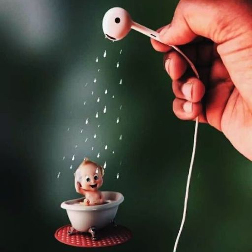 A creative setup with an earphone as a showerhead pouring tiny water droplets onto a miniature toilet