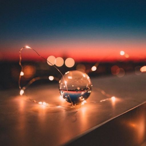 Crystal ball and fairy lights on a surface against a twilight sky