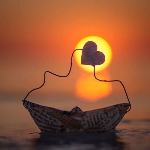 Paper boat and wire silhouette with a heart against a sunset backdrop