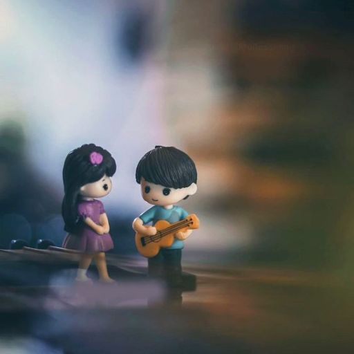 Two small figurines, a boy playing a guitar for a girl, with a blurred background