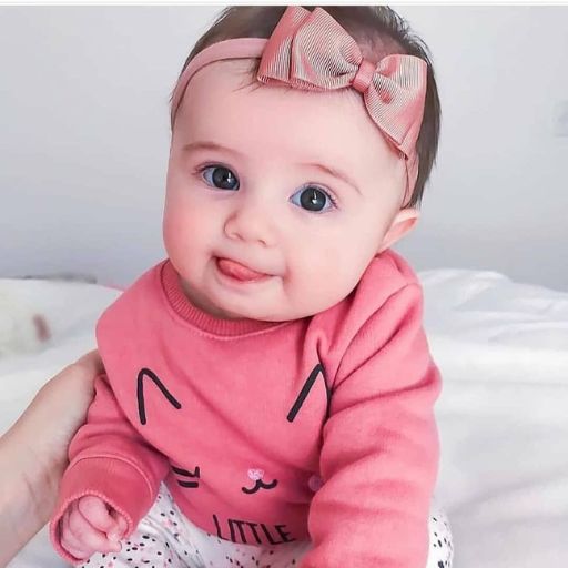 a baby with a pink shirt and a bow on her head