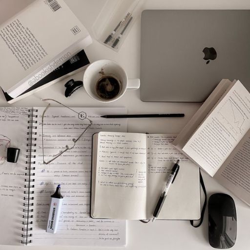 a desk with a laptop, notebook, and a cup of coffee