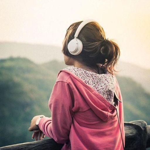 a girl with headphones looking out over a mountain