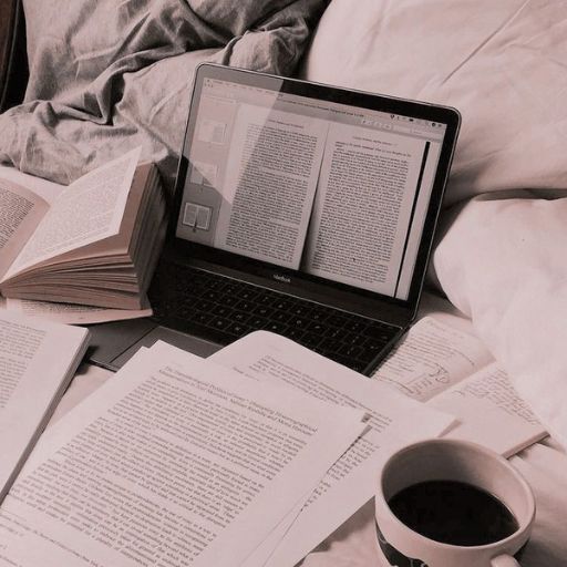 a laptop computer sitting on top of a bed next to a cup of coffee