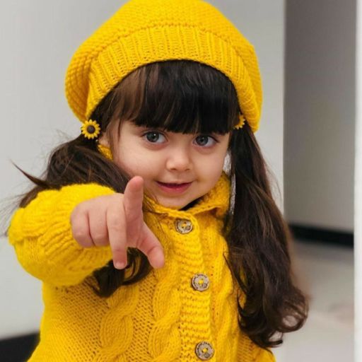 a little girl in a yellow coat pointing at the camera