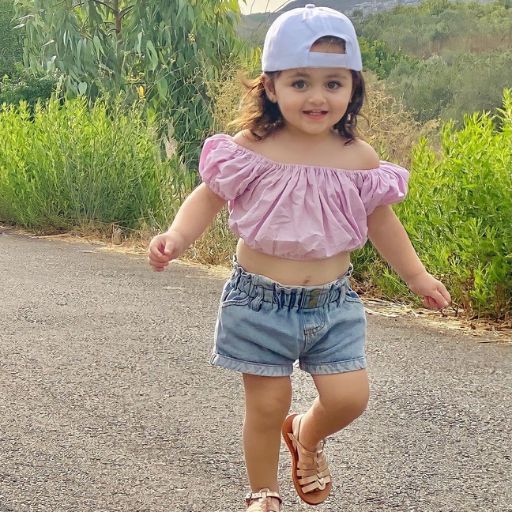 a little girl riding a skateboard down a road