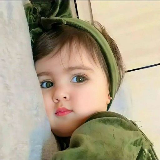 a little girl wearing a green dress and a green headband