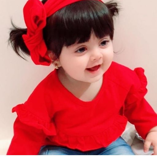 a little girl wearing a red shirt and a bow in her hair