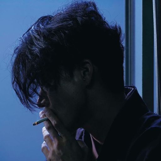 a man smoking a cigarette in front of a window