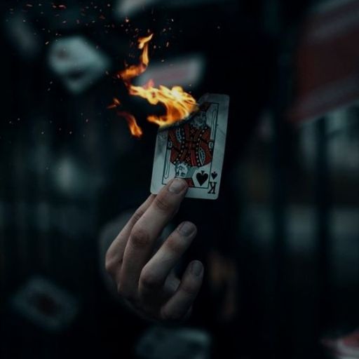 a person holding a burning playing card in their hand