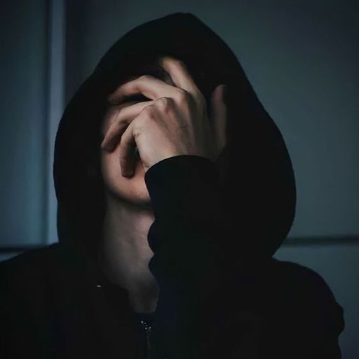 a person in a dark room with their hands on their face