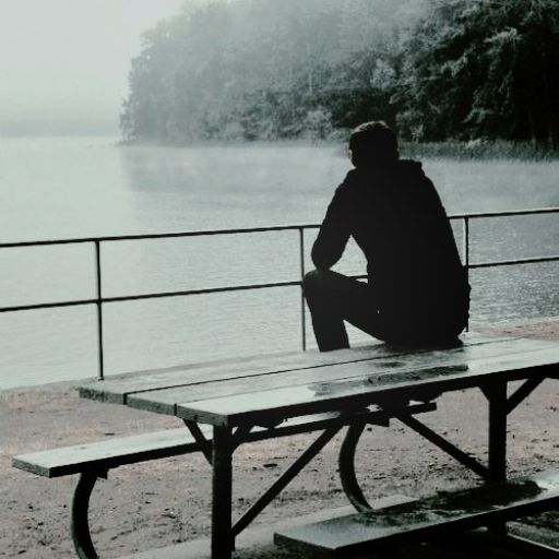 a person sitting at a picnic table near a body of water