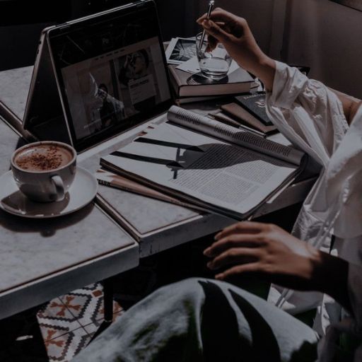 a person sitting at a table with a laptop and a cup of coffee