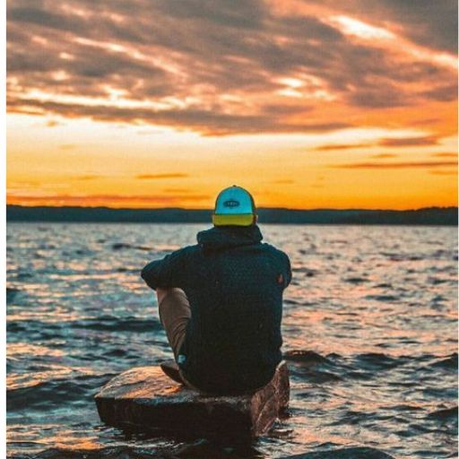 a person sitting on a rock in the water