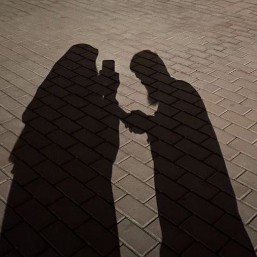 a shadow of two people using a cell phone