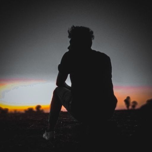 a silhouette of a person sitting on the ground