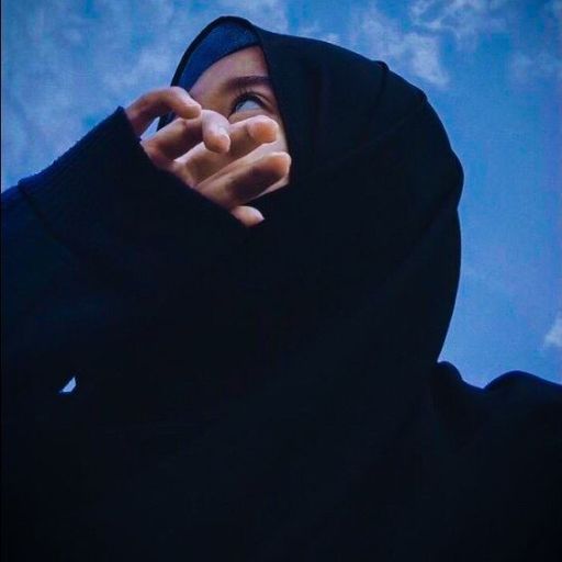 a woman in a black hoodie holding her hand up to the sky