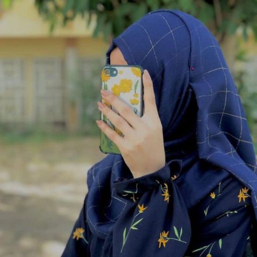 a woman in a blue hijab holding a cell phone