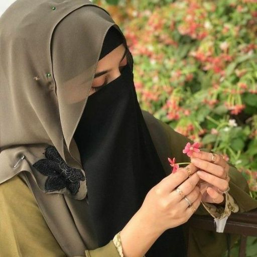 a woman in a hijab is holding a flower