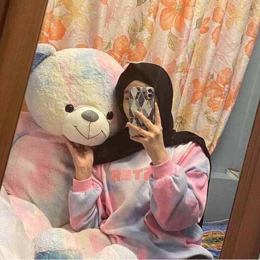 a woman in a pink hoodie is holding a teddy bear