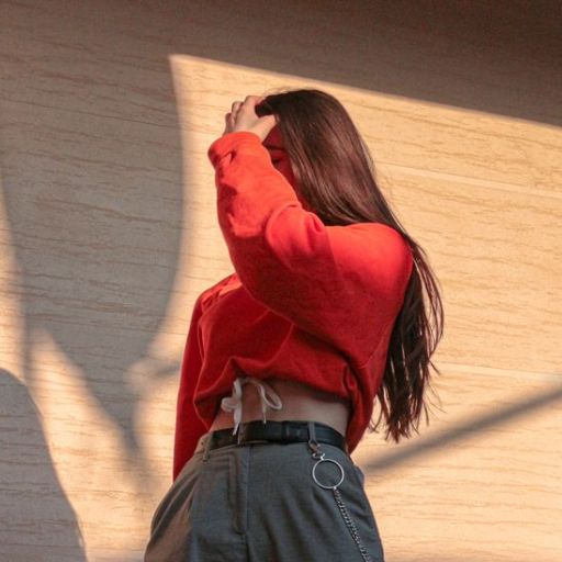 a woman in a red shirt is standing in front of a wall