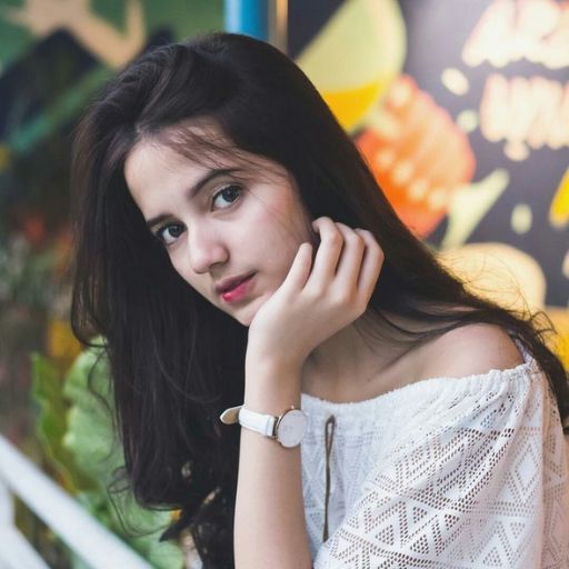 a woman in a white top leaning against a wall