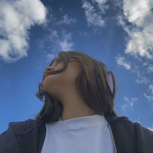 a woman looking up into the sky with clouds in the background