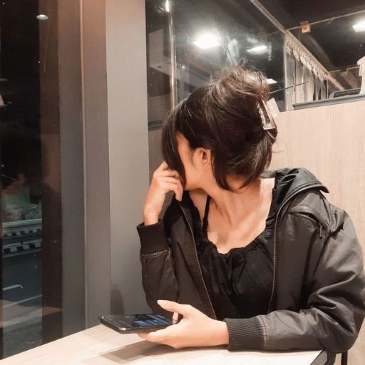 a woman sitting at a table using a cell phone