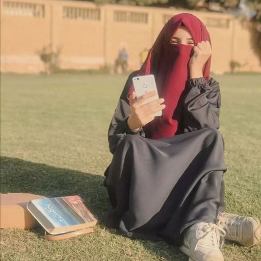 a woman sitting in the grass with a cell phone