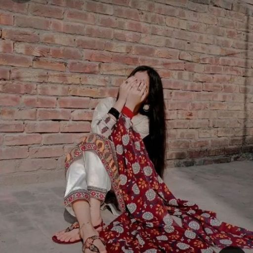 a woman sitting on the ground covering her face