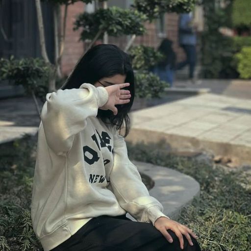 a woman sitting on the ground with her hand on her face