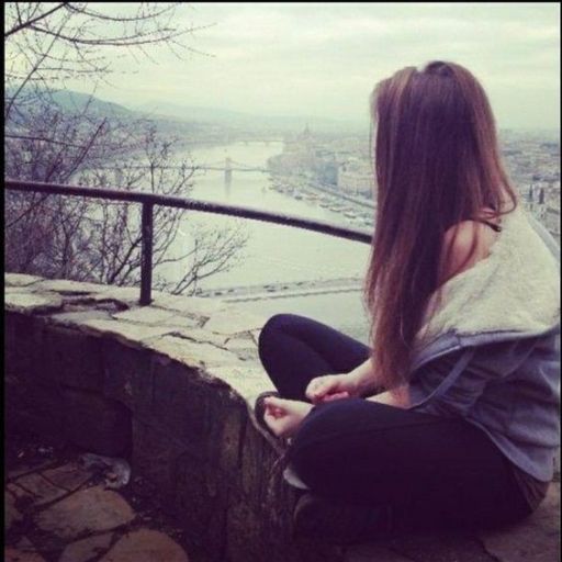 a woman sitting on top of a stone wall next to a river