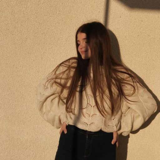 a woman standing in front of a wall with her hands on her hips