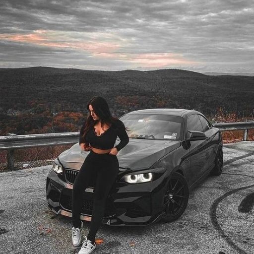 a woman standing next to a black car