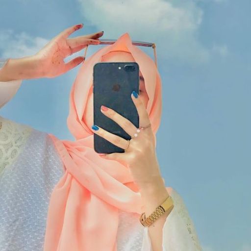 a woman wearing a hijab taking a picture with her phone