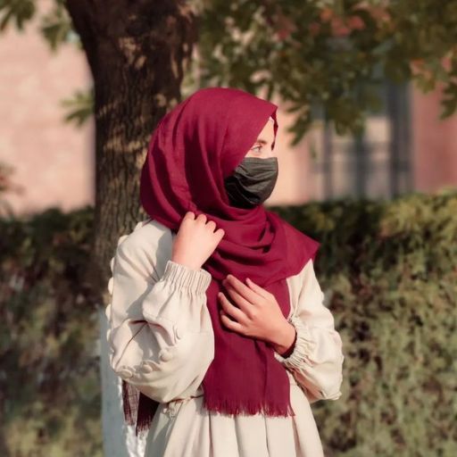 a woman wearing a red scarf standing next to a tree