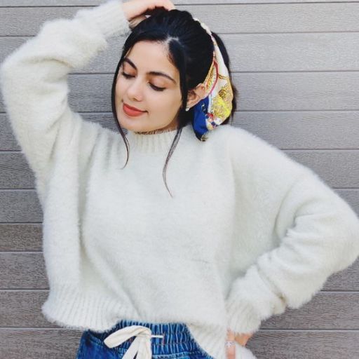 a woman wearing a white sweater and blue shorts