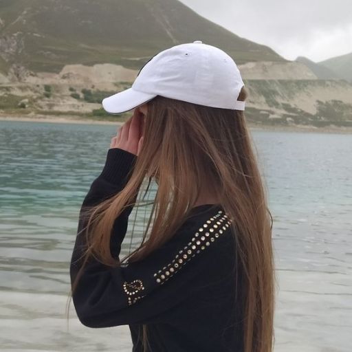 a woman with long brown hair wearing a white hat