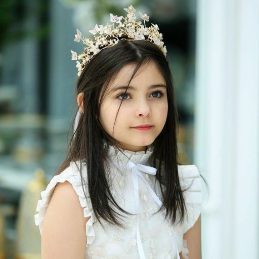 a young girl wearing a white dress and a tiara