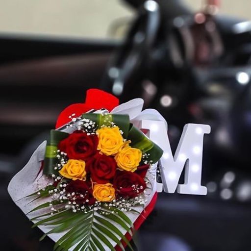 A bouquet of red and yellow roses with baby's breath and greenery, with a blurred background