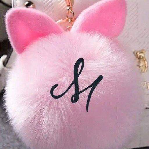 A fluffy pink keychain with bunny ears and a cursive initial _J_ displayed on a textured background