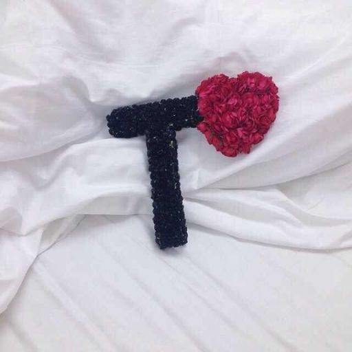 A hammer with a black handle and a head made of red flowers on a white fabric background