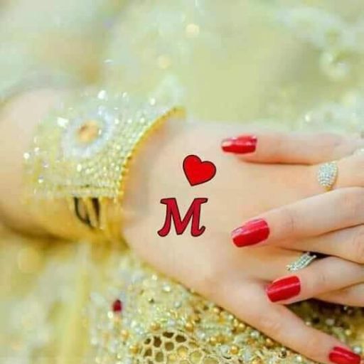 A hand with red nail polish and a ring, resting on another hand with a beaded cuff, adorned with a heart and the letter 'M' tattoo