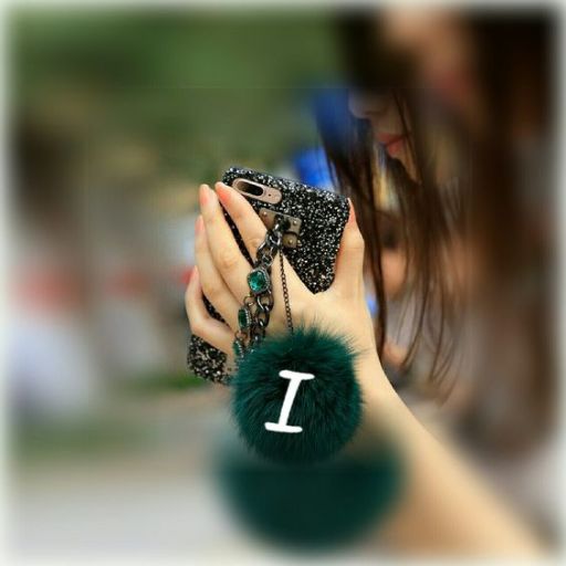 A person holding a glittery phone with a green pom-pom accessory